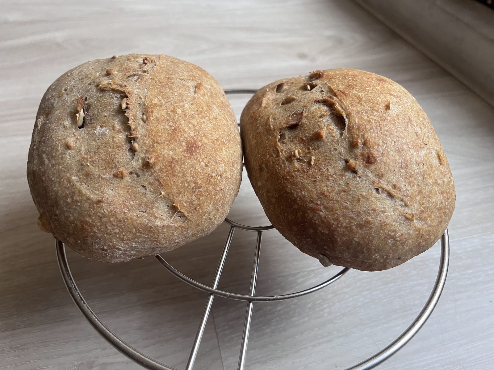 Two seeded sourdough loaves on a cooling rack