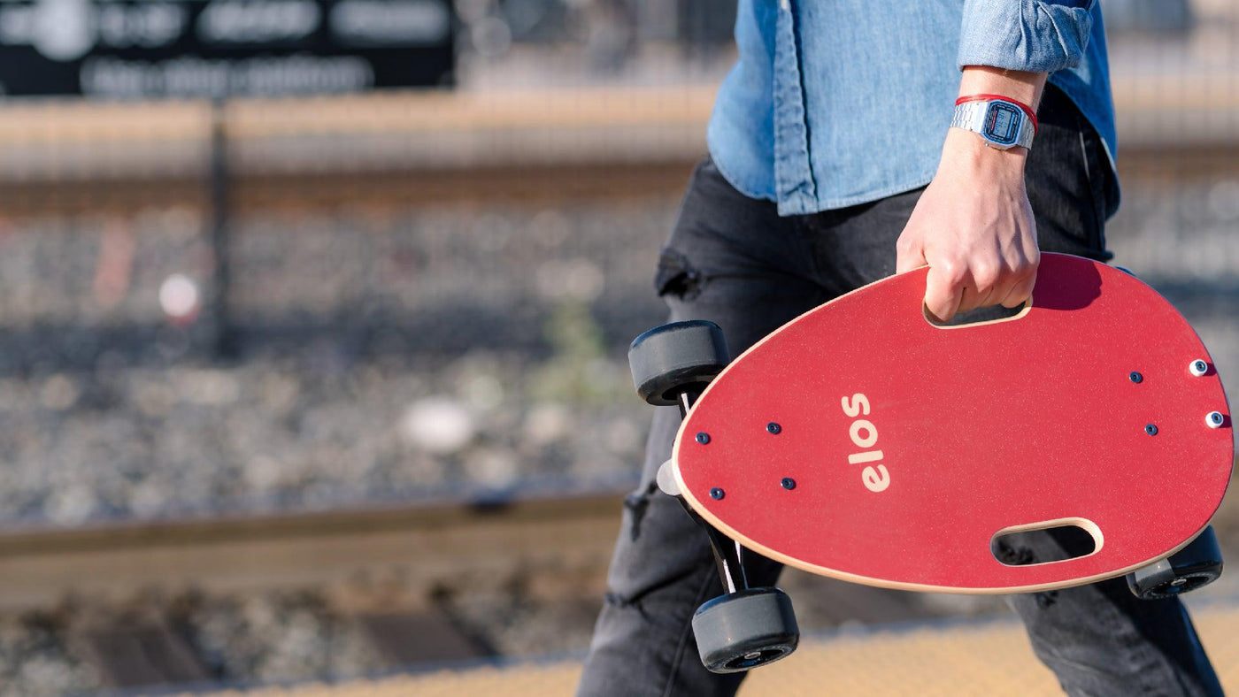 Someone carrying a red Elos board by its handle