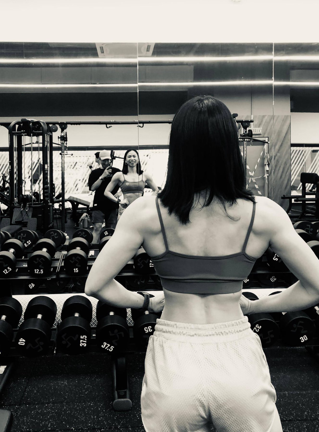 Spring at the gym, seen from behind, facing a mirror
