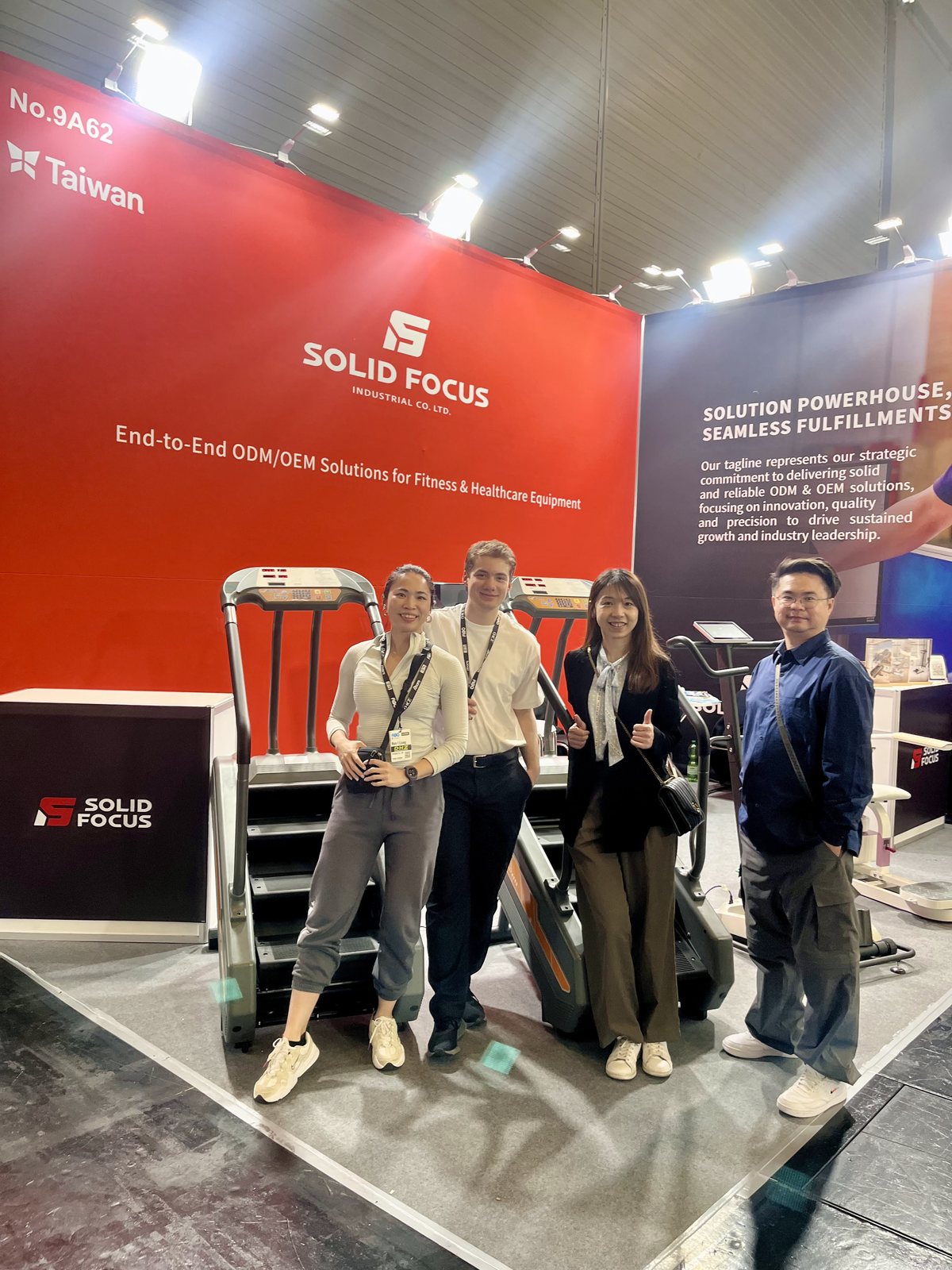 Spring and three others at the SolidFocus booth, in front of a red SolidFocus wall